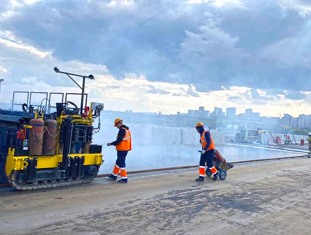 Cast asphalt is being laid on the cable-stayed section of a bridge under construction in Novosibirsk